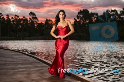 Beautiful Young Woman In The Gardens Wearing A Long Silk Red Dress Stock Photo