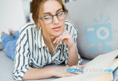 Beautiful Young Woman Reading A Book At Home Stock Photo