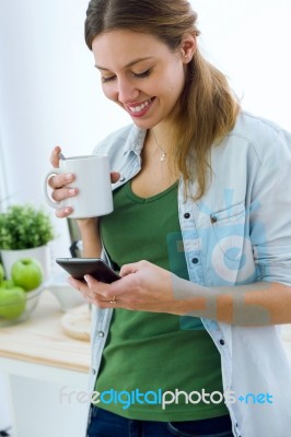 Beautiful Young Woman Using Her Mobile Phone And Enjoying Breakf… Stock Photo