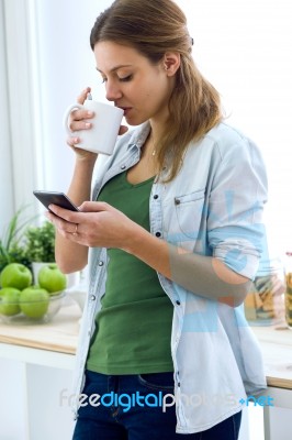 Beautiful Young Woman Using Her Mobile Phone And Enjoying Breakf… Stock Photo