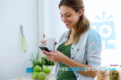 Beautiful Young Woman Using Her Mobile Phone And Enjoying Breakf… Stock Photo