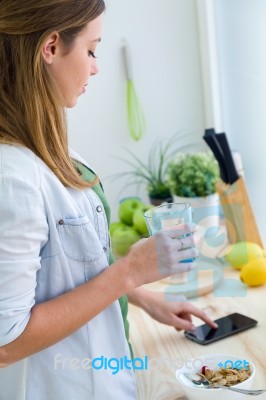 Beautiful Young Woman Using Her Mobile Phone And Enjoying Breakf… Stock Photo