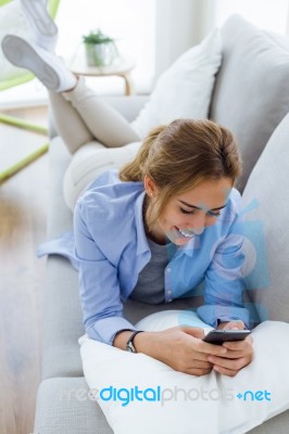 Beautiful Young Woman Using Her Mobile Phone At Home Stock Photo