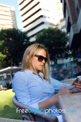 Beautiful Young Woman Using Her Mobile Phone In A Restaurant Ter… Stock Photo