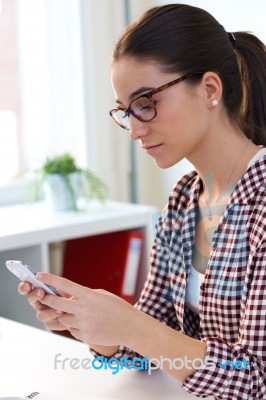 Beautiful Young Woman Using Her Mobile Phone In The Office Stock Photo