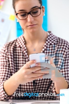 Beautiful Young Woman Using Her Mobile Phone In The Office Stock Photo