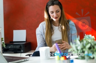 Beautiful Young Woman Using Her Mobile Phone In The Office Stock Photo