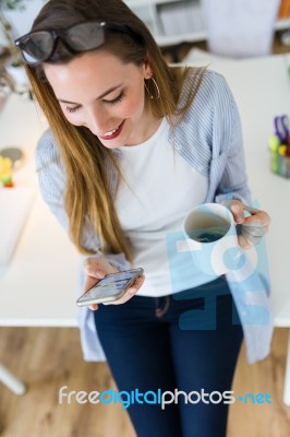 Beautiful Young Woman Using Her Mobile Phone In The Office Stock Photo