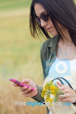 Beautiful Young Woman Using Her Mobile Phone In The Park Stock Photo