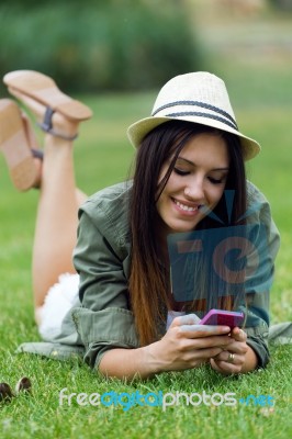 Beautiful Young Woman Using Her Mobile Phone In The Park Stock Photo