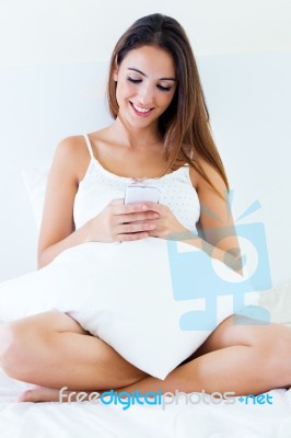 Beautiful Young Woman Using Mobile Phone On Bed Stock Photo