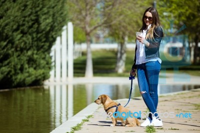 Beautiful Young Woman With Her Dog Using Mobile Phone Stock Photo