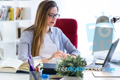 Beautiful Young Woman Working With Laptop In Her Office Stock Photo