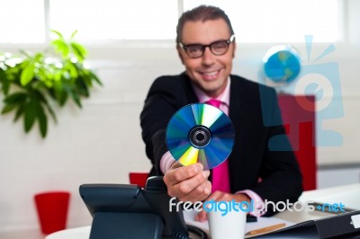 Bespectacled Boss Presenting A Compact Disk Stock Photo