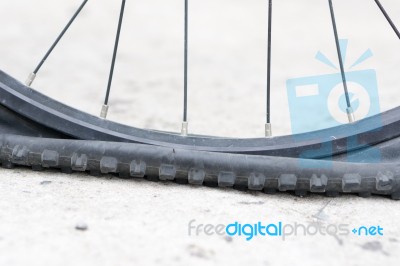 Bicycle Wheel With Flat Tyre On The Concrete Road Stock Photo