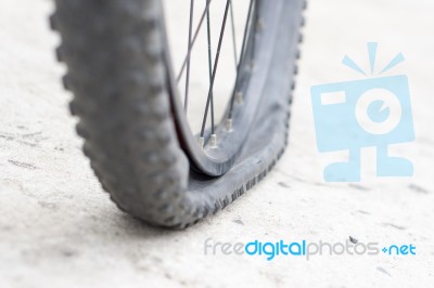 Bicycle Wheel With Flat Tyre On The Concrete Road Stock Photo