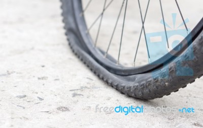 Bicycle Wheel With Flat Tyre On The Concrete Road Stock Photo