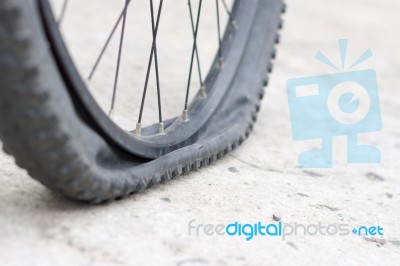 Bicycle Wheel With Flat Tyre On The Concrete Road Stock Photo