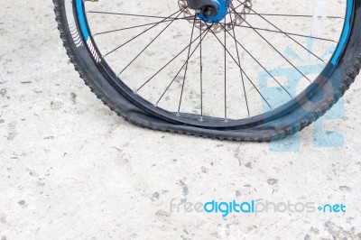 Bicycle Wheel With Flat Tyre On The Concrete Road Stock Photo