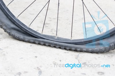 Bicycle Wheel With Flat Tyre On The Concrete Road Stock Photo