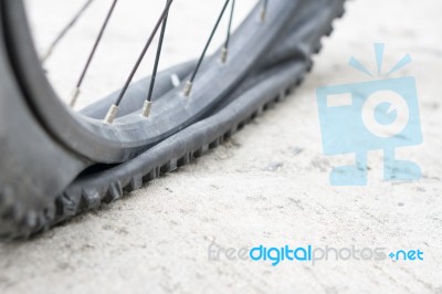 Bicycle Wheel With Flat Tyre On The Concrete Road Stock Photo