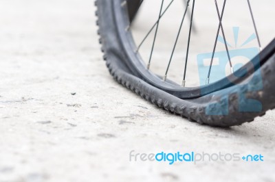 Bicycle Wheel With Flat Tyre On The Concrete Road Stock Photo