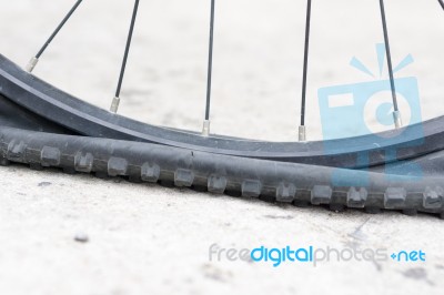 Bicycle Wheel With Flat Tyre On The Concrete Road Stock Photo