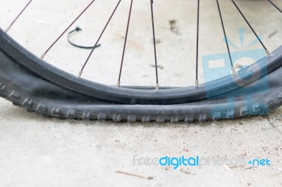 Bicycle Wheel With Flat Tyre On The Concrete Road Stock Photo