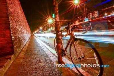 Bicycles Parked In The Street With Lights At Night Stock Photo