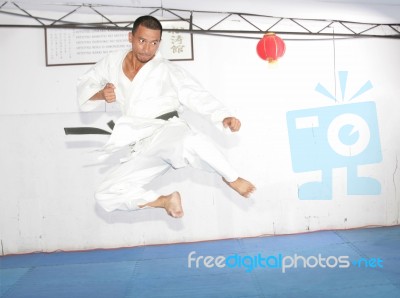 Black Belt Karate Man Jumping To Give A High Kick Stock Photo