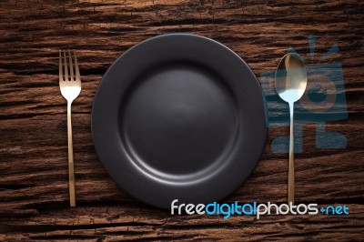 Black Empty Plate Fork Spoon On Wooden Table Background Stock Photo