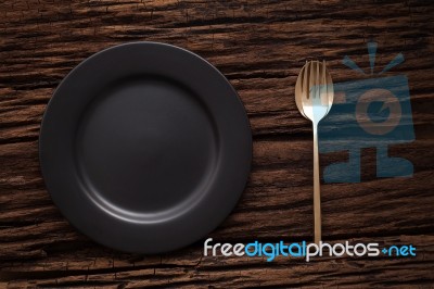 Black Empty Plate Fork Spoon On Wooden Table Background Stock Photo