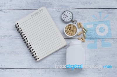 Blank Notebook And Herb Capsule With Vintage Watch And Plastic Container Stock Photo