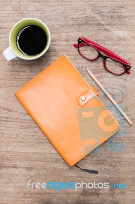 Blank Orange Leather Diary,glasses And A Cup Of Coffee On Wooden Desk Stock Photo