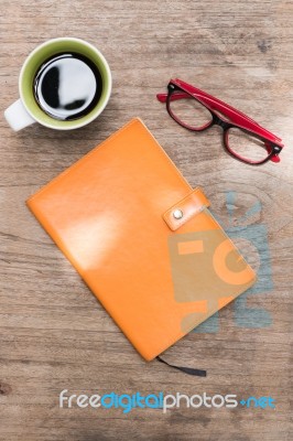 Blank Orange Leather Diary,glasses And A Cup Of Coffee On Wooden Desk Stock Photo