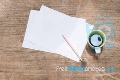 Blank Paper With Pencil And A Cup Of Coffee On Wood Table Stock Photo