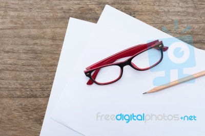 Blank Paper With Pencil And Eye Glasses On Wood Table Stock Photo