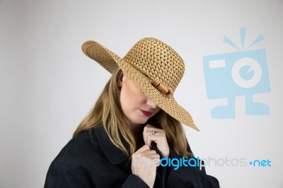 Blonde Female In Large Hat And Coat Hiding Face Stock Photo