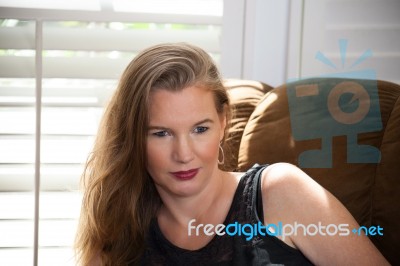 Blonde Female Sitting On Large Chair Stock Photo