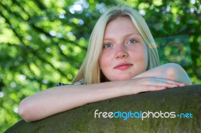 Blonde Girl Leaning On Branch In Nature Stock Photo