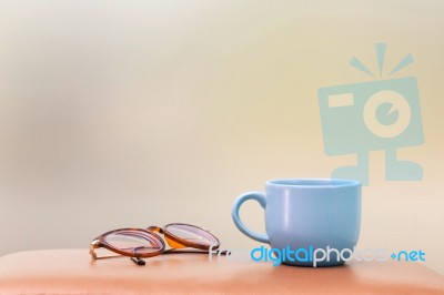 Blue Cup And Eyeglass On The Table Stock Photo