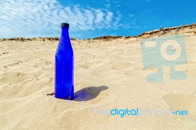 Blue Water Bottle In Dry Yellow Sand Stock Photo