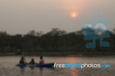 Blurred Image Of People Paddling Boat In Pond With Sunset In Par… Stock Photo