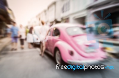 Blurred Pink Car On The Road With People Stock Photo