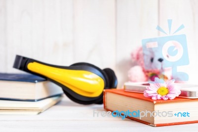 Books Or Journal And Earphone With Flowers Arranged On A Neutral White Painted Desk Stock Photo