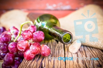 Bottle Of Red Wine, Grape And Corks On Wooden Table Stock Photo