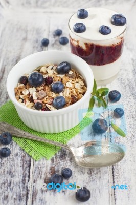 Bowl Of Muesli With Fresh Blueberries And Glass Of Yogurt On Whi… Stock Photo