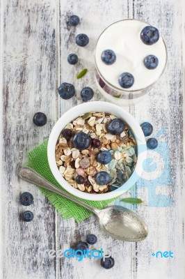 Bowl Of Muesli With Fresh Blueberries And Glass Of Yogurt On Whi… Stock Photo