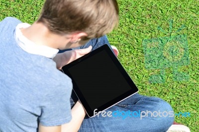 Boy With Touch Pad Sitting On Meadow Stock Photo