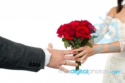 Bride Offering Rose Bouquet To The Groom Stock Photo